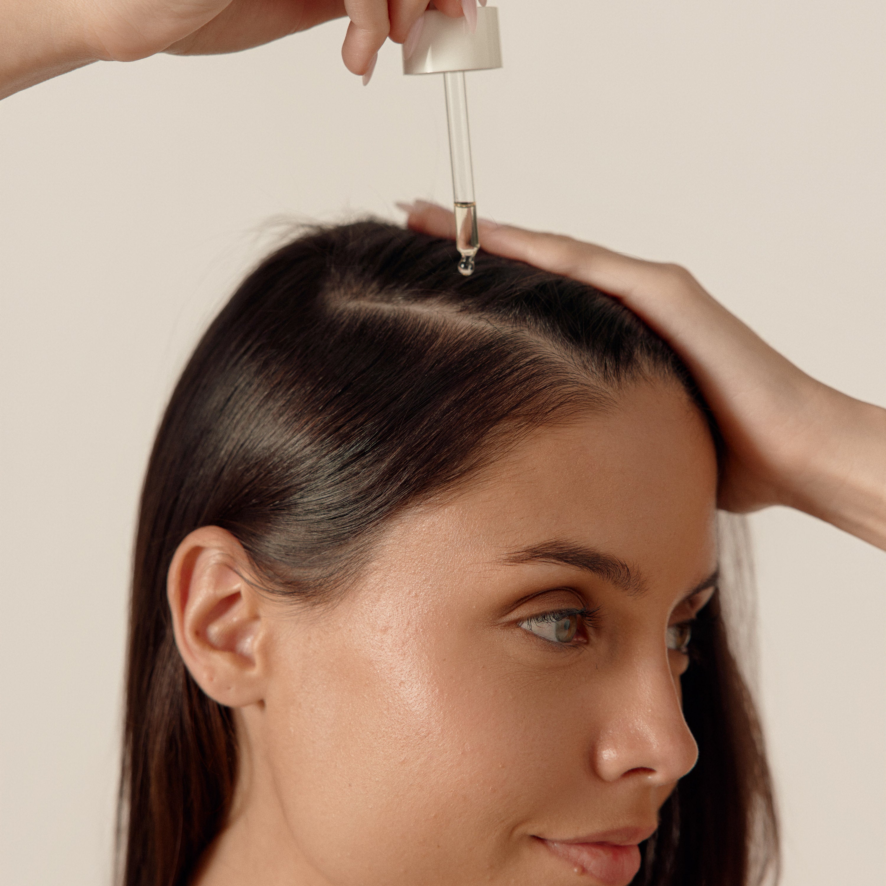 femme qui tient une pipette sur ses cheveux en regardant la caméra