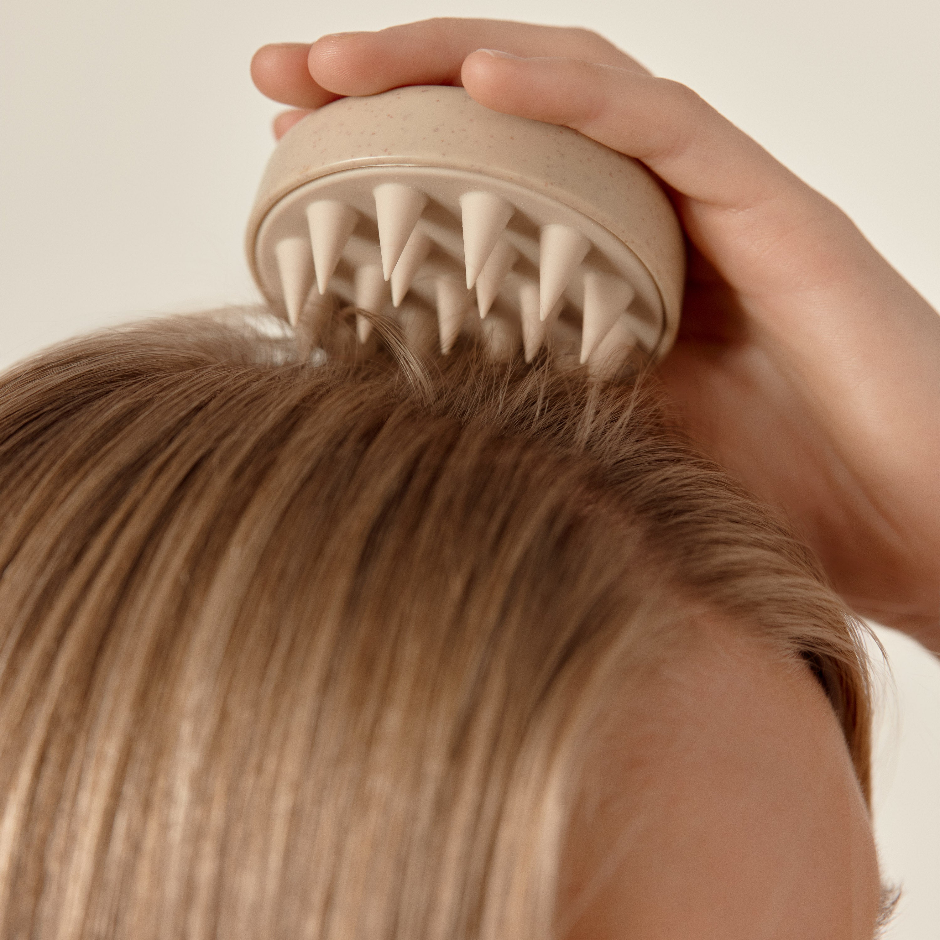femme qui se passe une brosse massante à picôts sur le cuir chevelu