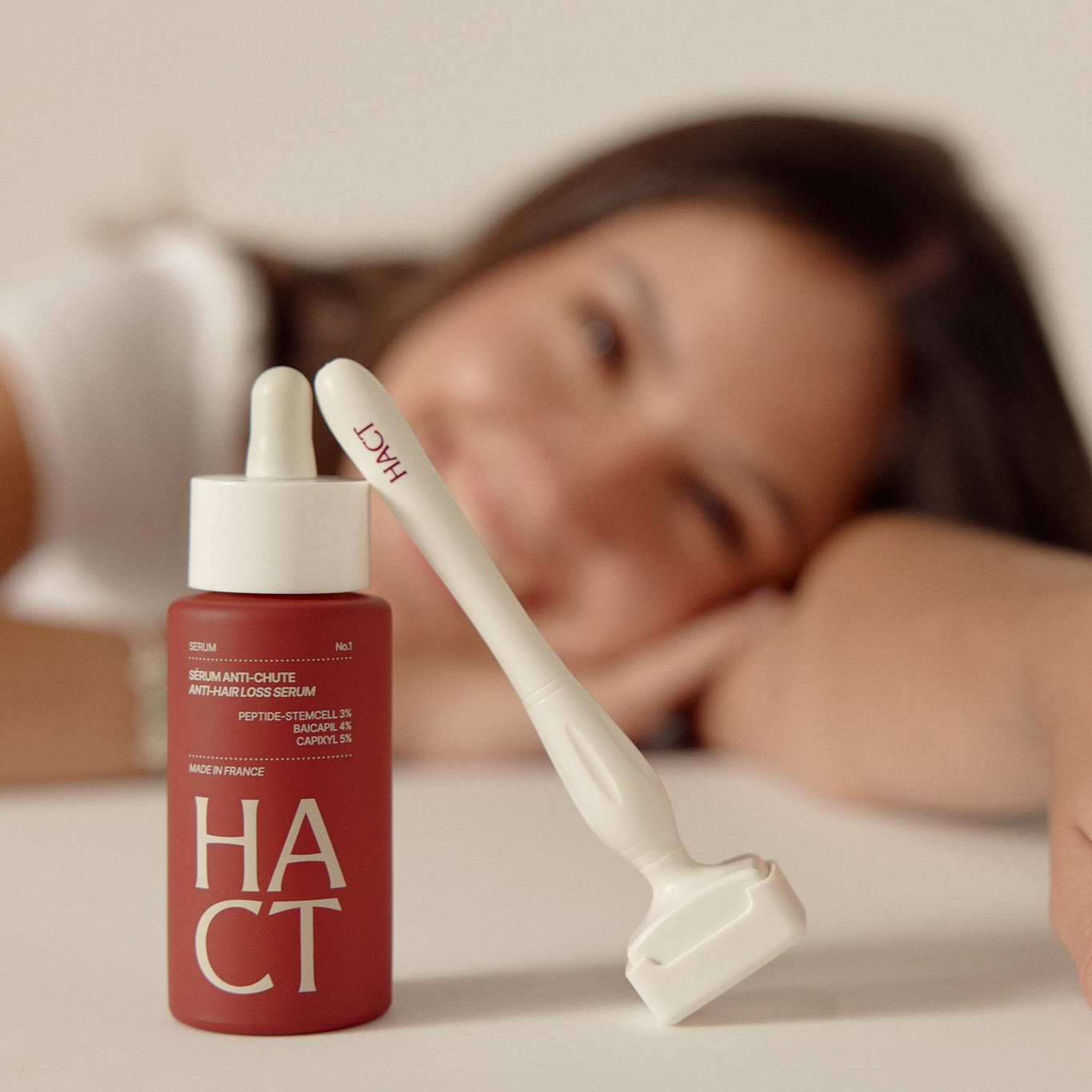 femme qui souri derrière un flacon de sérum et un dermastamp