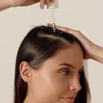 femme qui tient une pipette sur ses cheveux en regardant la caméra