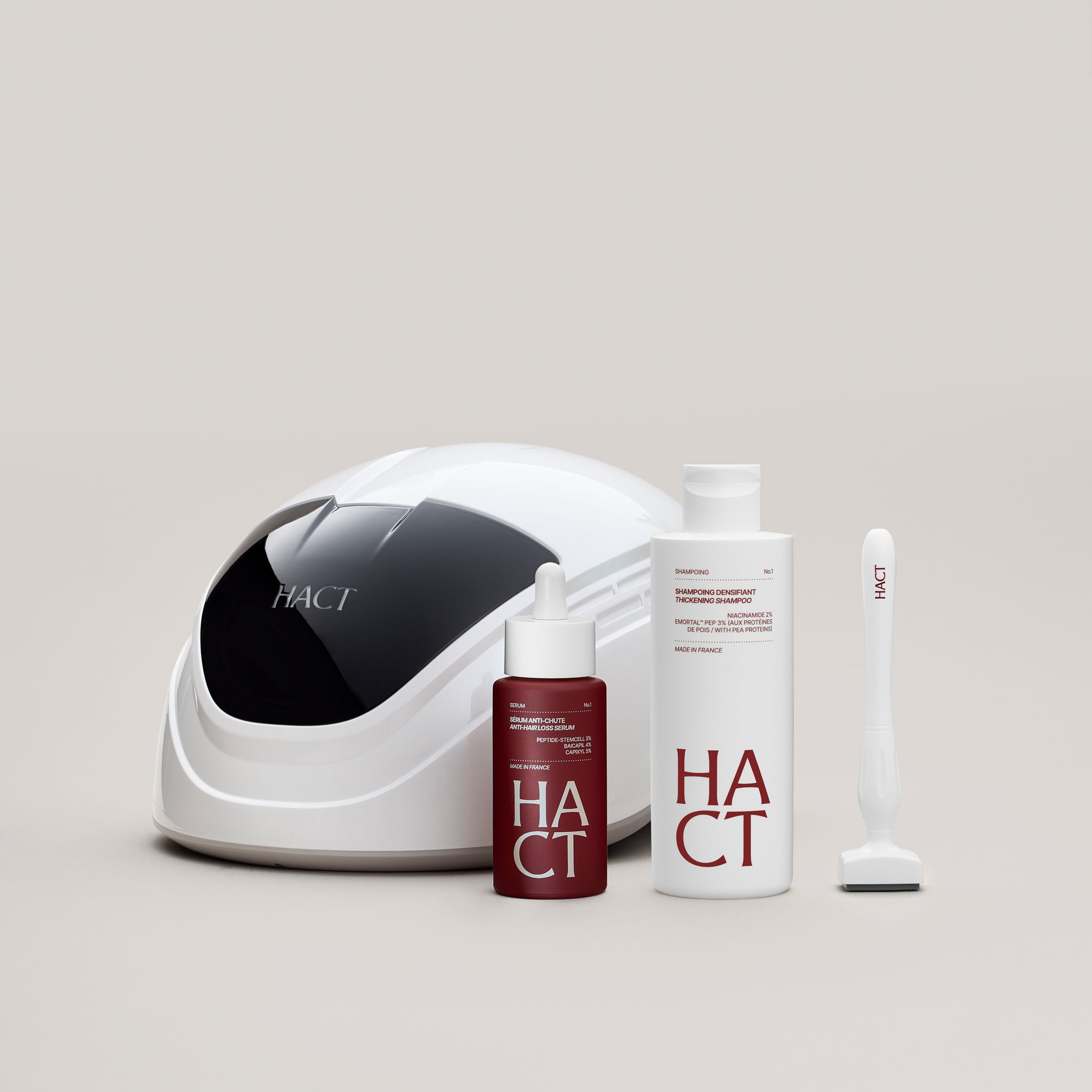 casque à laser derrière un flacon de sérum, un flacom de shampoing et un dermastamp